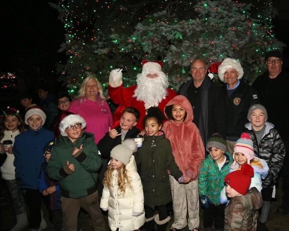 Debby Izzo, of the Bellmore Chamber of Commerce; a well-known man in a red suit; Hempstead Town Councilman Chris Carini; Nassau County Legislator Steve Rhoads and chamber President Jim Spohrer with a crowd of children at the tree lighting on Dec. 3.