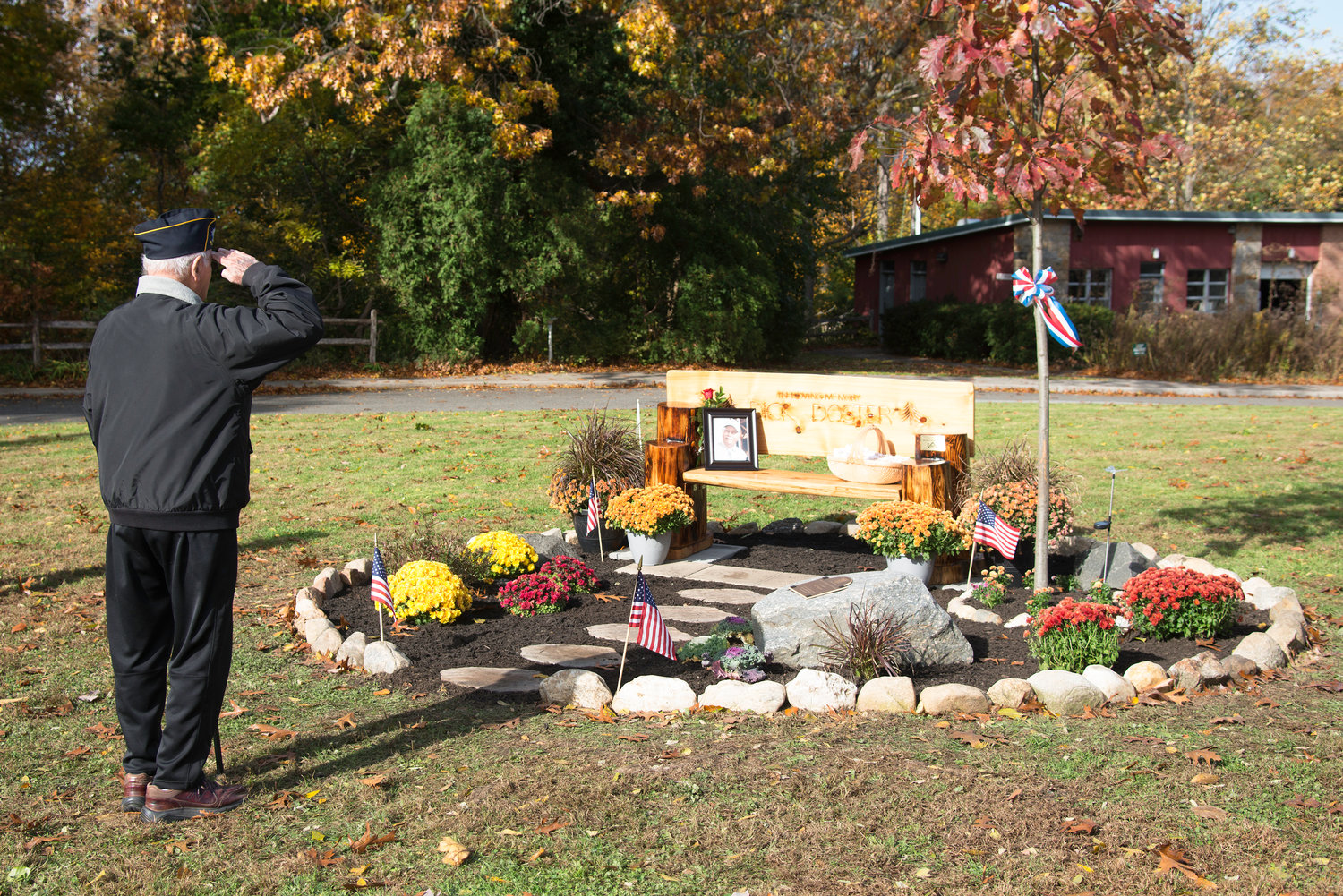 A veteran saluted the memorial to Richard Doster, which includes a red oak tree, a bench and flowers.