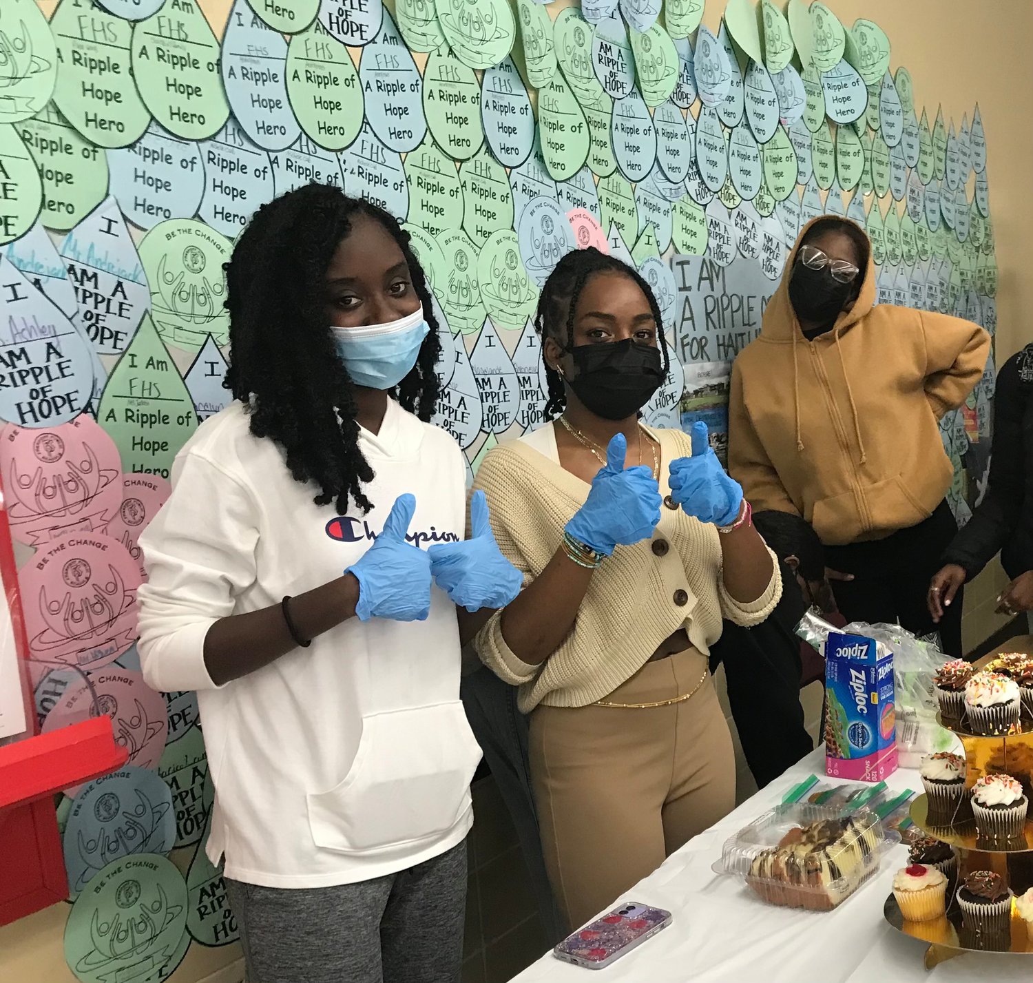 From left, members of the Freeport High School Human Relations Club,  Gracelyn Jean-Baptiste, Anya Simon and Hope Coardes, helped raised funds for the Haitian nonprofit, Association for the Children of Regnier Haiti, by selling paper drops to students in which an impressive Current of Collective Hope was created on the wall in the school’s cafeteria.