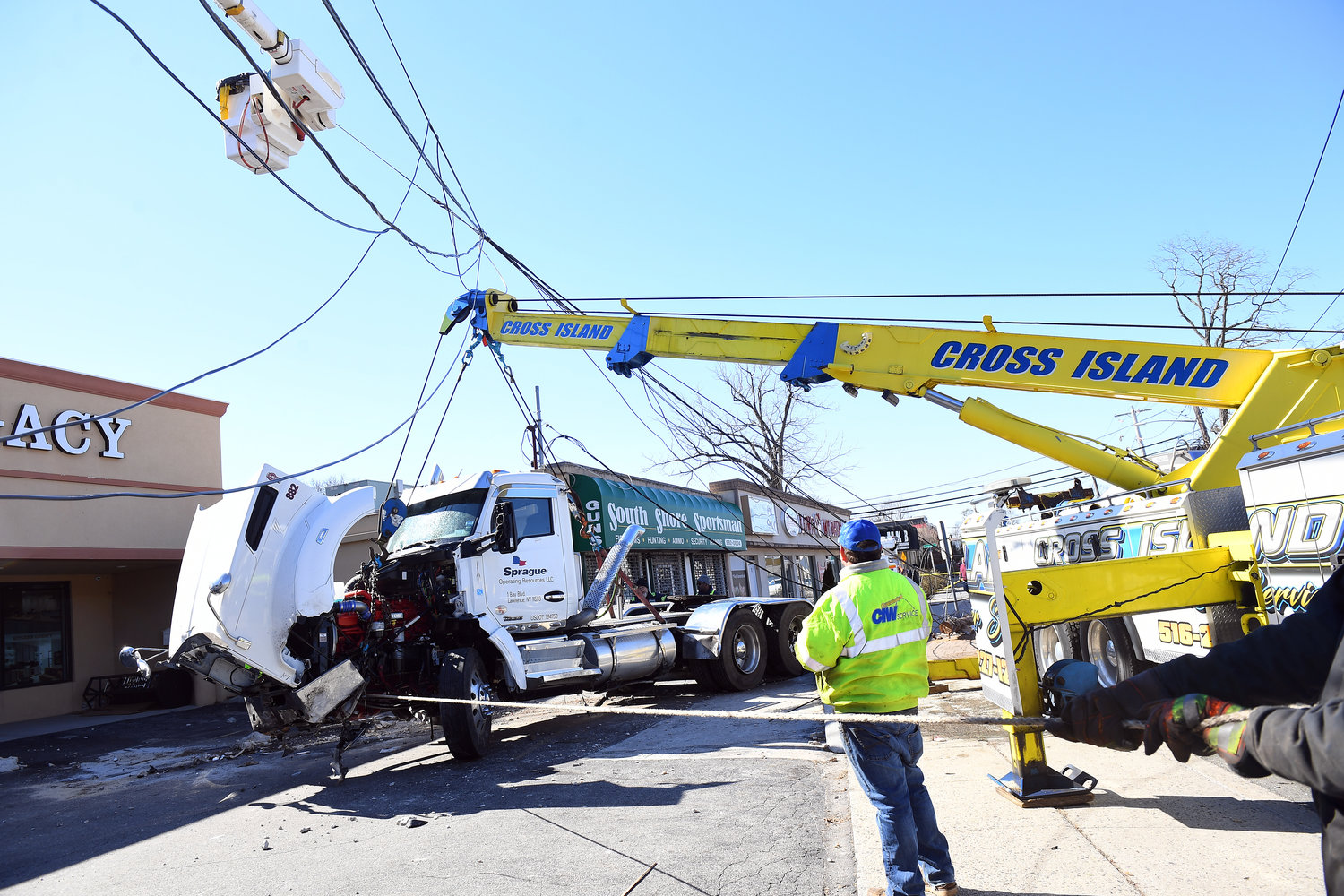 The Nassau County Police Department, PSEG Long Island, and other cleanup crews were on the scene this morning, assessing damage and diverting traffic. The truck, pictured, was carefully lifted and removed from the scene sometime after 10 a.m.