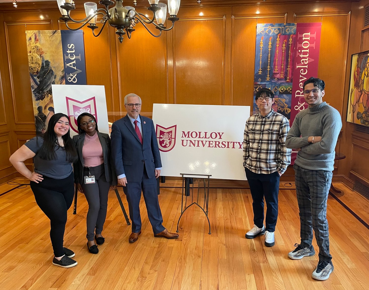 Molloy College president James Lentini shows students the new logo for Molloy University.