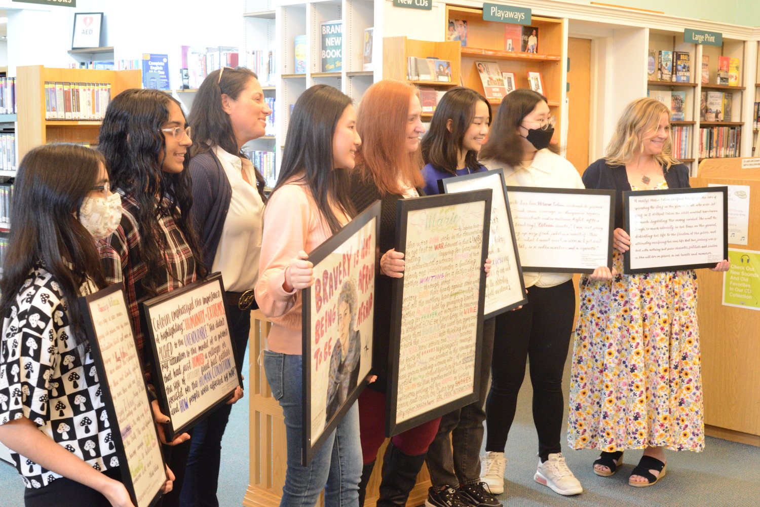 Members of Girl Pride International with their contributions to the Marie Colvin Art Exhibit at the Oyster Bay-East Norwich Library on March 25, when they were recognized for their participation.