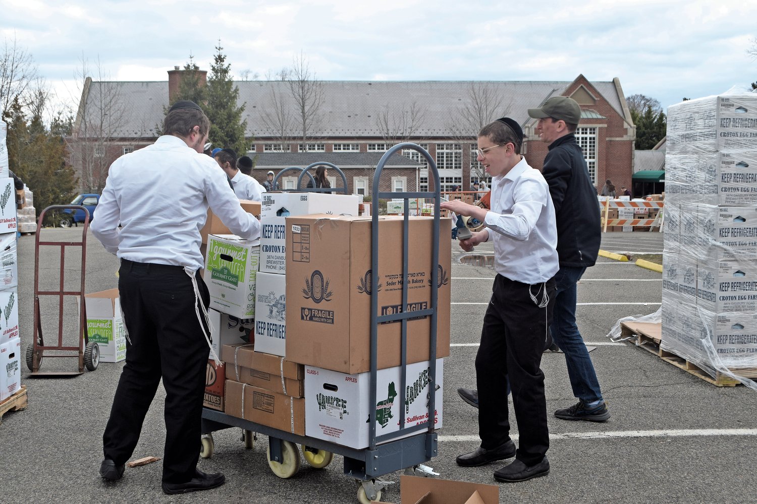 Meshulm Klugman, 15, left, and Chaim Klugman, 13, two of Rabbi Simcha Lefkowitz’s grandchildren, checked boxes with food orders and taped them closed.