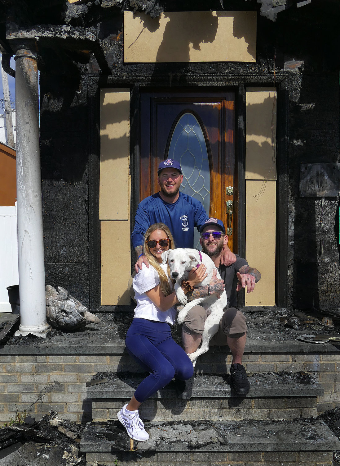 Daisy with her owners Bennett O’ Donnell and Kathleen Dulligan and their neighbor, Keith Carr, in front of his fire-stricken house.
