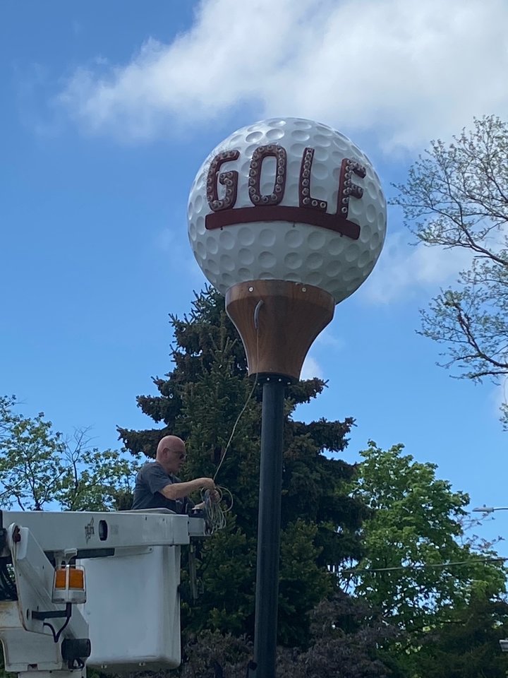 Baldwin Historical Society president Gary Farkash securing the golf ball while in a cherry picker next to the historical society museum.