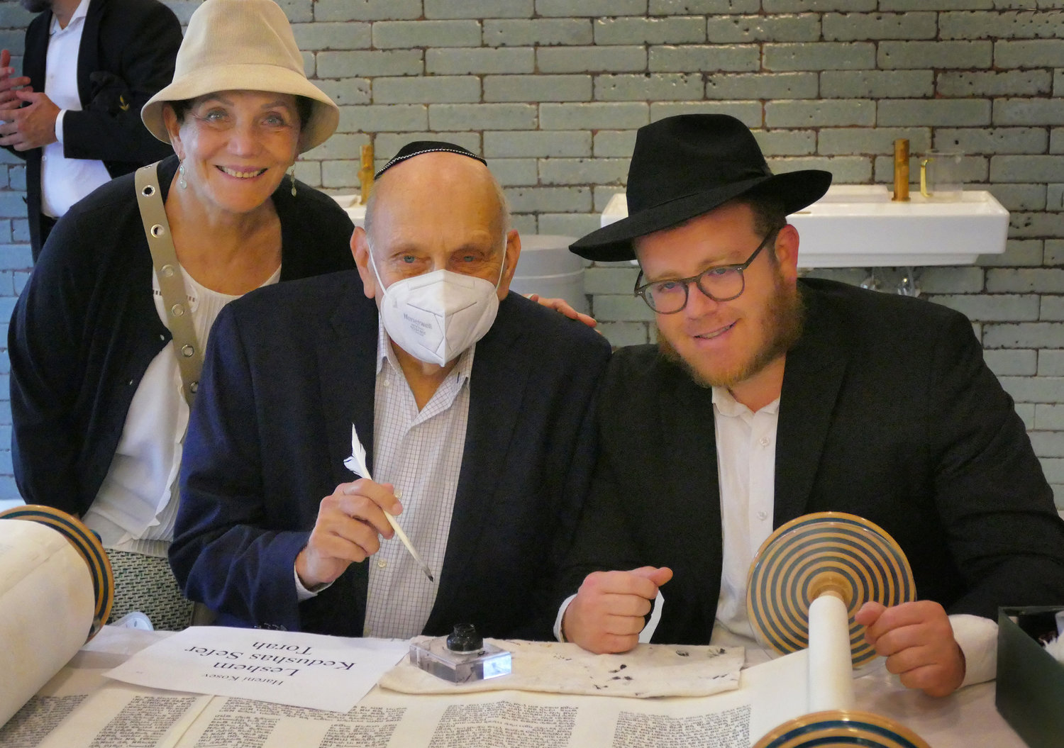 Elaine and Norm Brodsky, who made a donation to acquire a second torah, looked over the holy scroll with Assistant Rabbi Yechiel Winfeld.