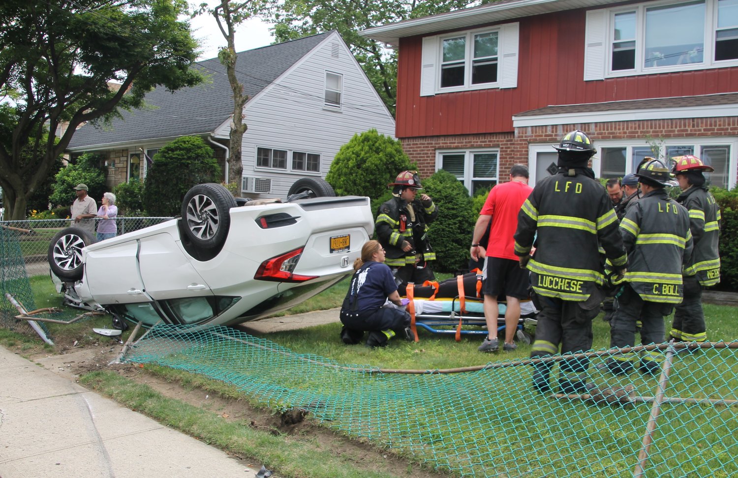 Lynbrook Emergency Medical Company members secured the driver of an overturned vehicle on a stretcher on the front lawn of a house on the corner of Ocean and Merton avenues on June 11.