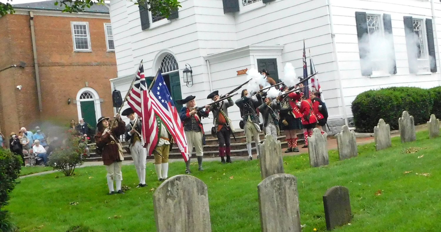 The 3rd NY Regiment reenacted the firing of muskets on the grounds of St. George’s Church in Hempstead during the American Revolutionary War. To the viewer’s right, representing the British redcoats, are the reenactment members of the 42nd Highland Regiment.