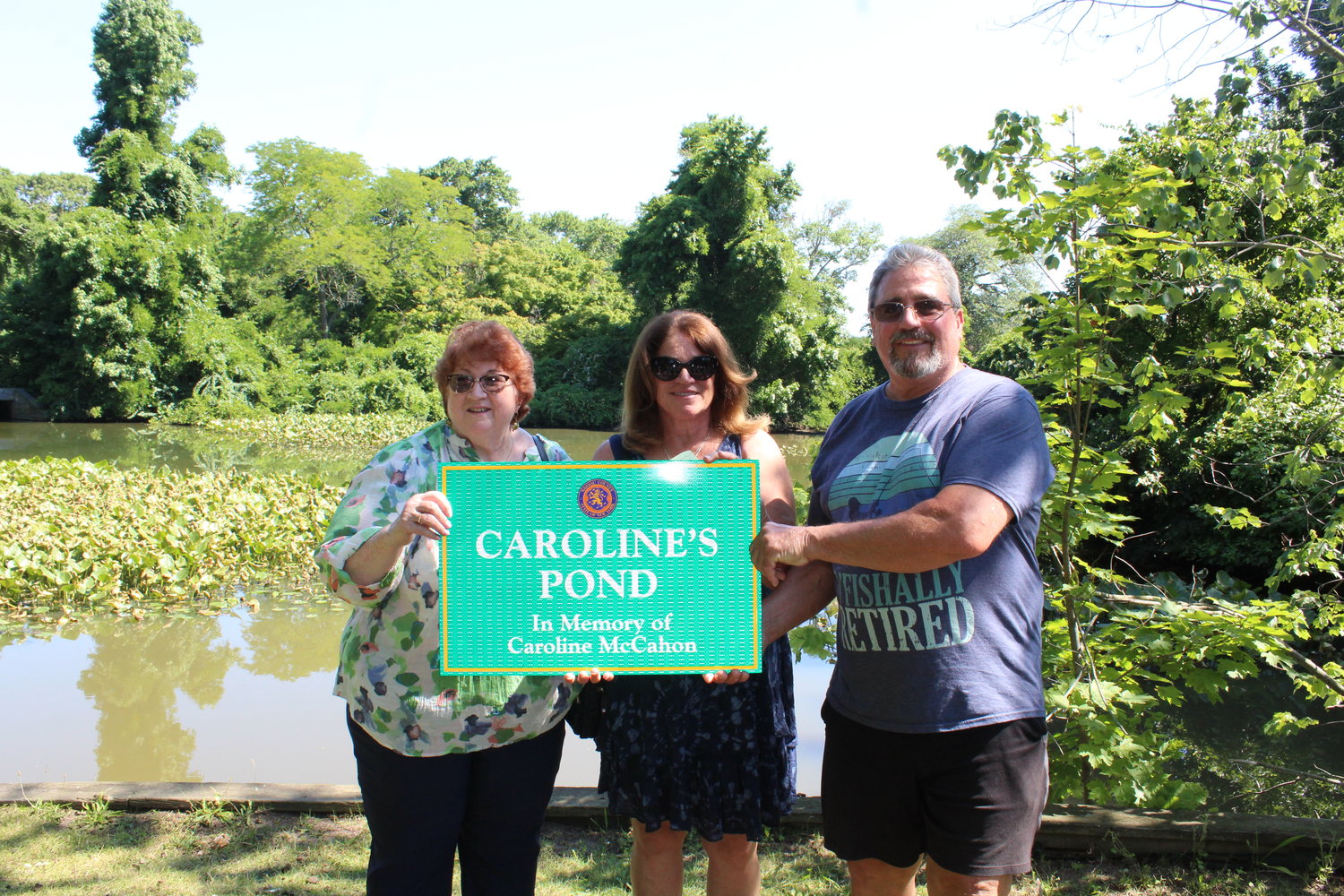 Caroline McCahon’s family — Ellen Plossl, Julie Slotkin and Daniel McCahon — with the miniature Caroline’s Pond marker that was presented to them.