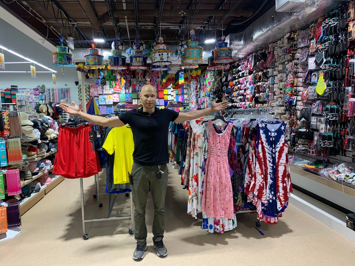 Grand 99¢ Plus manager Moazzal Ali showing the selection of clothing,        accessories, and some of the party supplies.