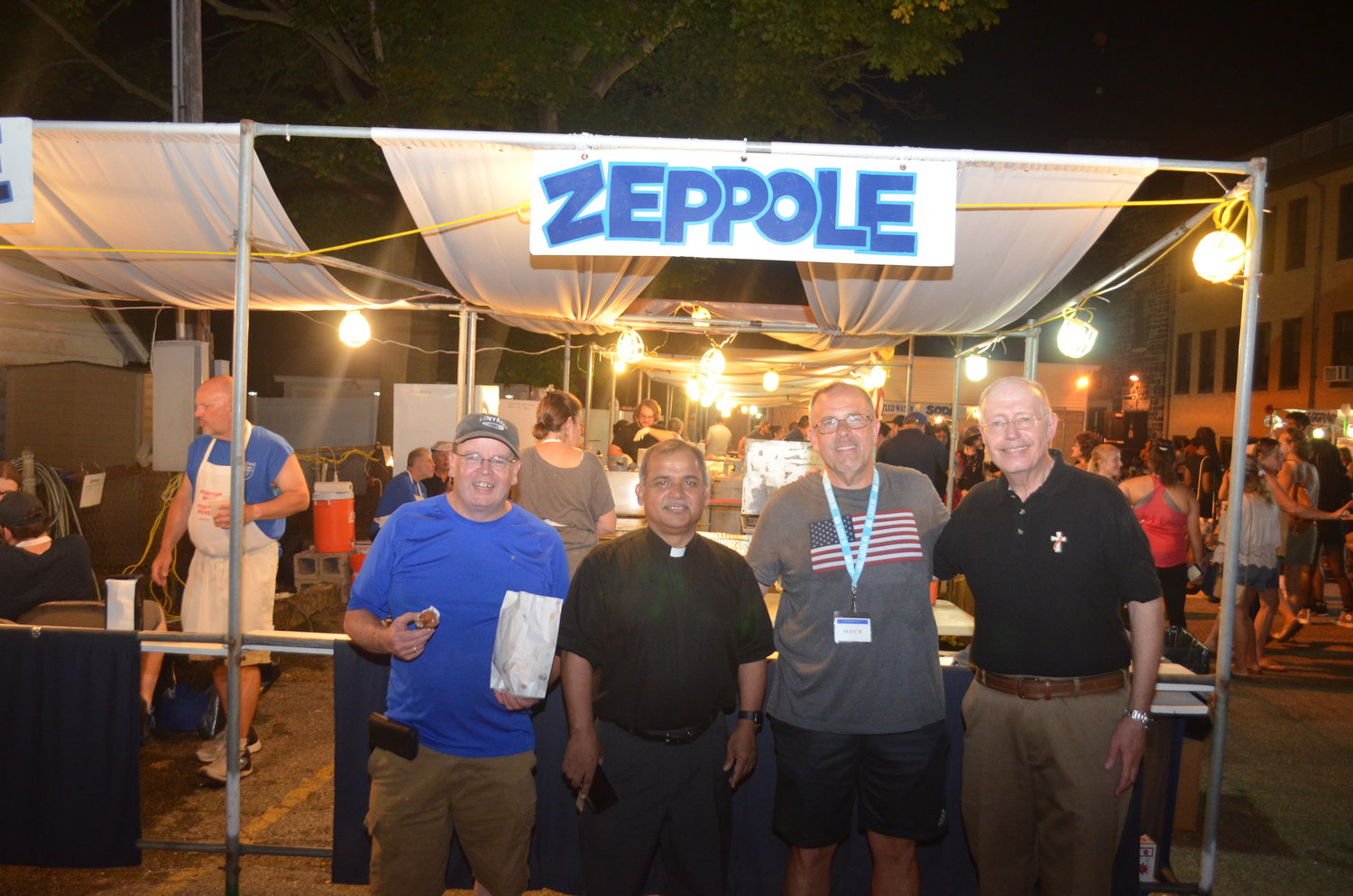 Volunteer Paul Cavana, Pastor Johnny Mendonca, feast chairperson Michael Cecery, and Deacon Ralph Muscente enjoying some zeppoles.