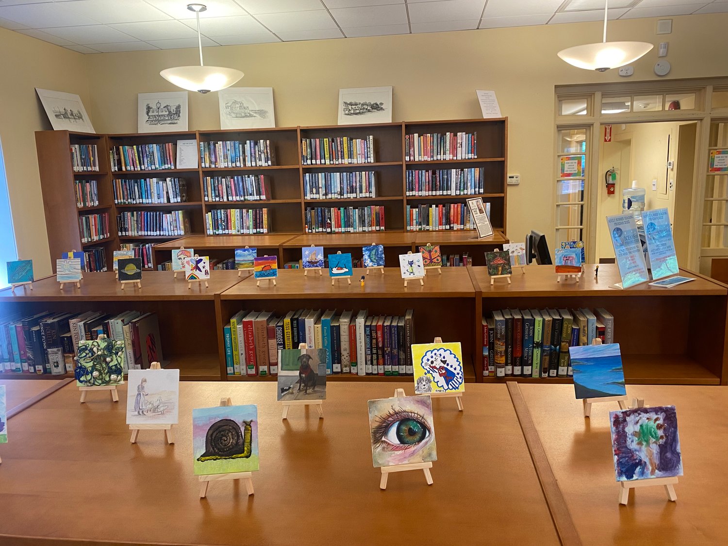 The artwork from the Tiny Art Show created by children, teenagers and adults is on display on top of the bookshelves near the entrance of the Bayville Library.