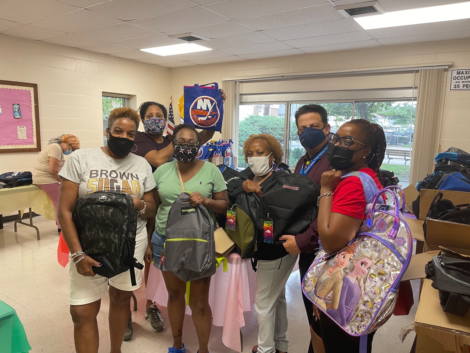 Claudine Hall, pictured third from right preparing for last year’s backpack giveaway, said the goal of the annual program is to serve local students and families from all the schools and areas in Elmont.
