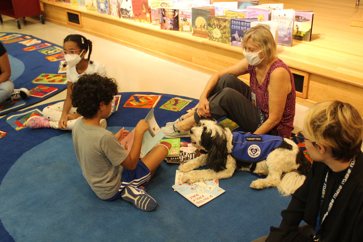 Aiden Lopez, 9, reads to Eli and his owners Martha and Maureen Garvey.