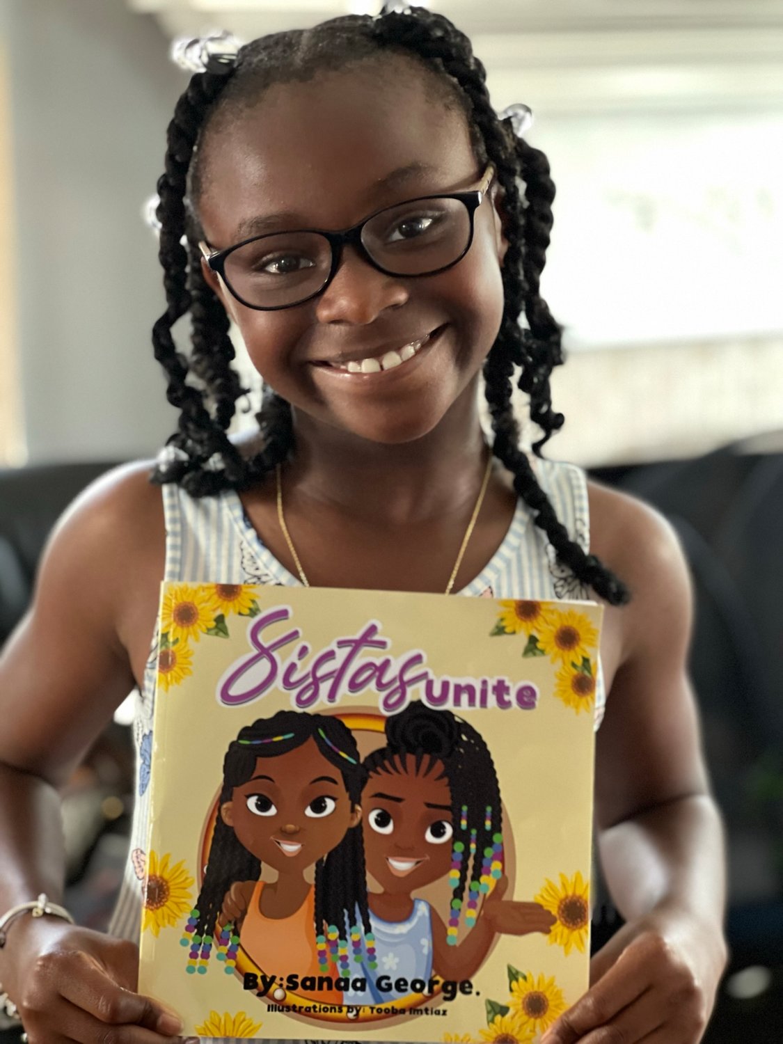 Nine-year-old Sanaa George holds up her book Sistas Unite, a tale of facing your fears of taking the Covid-19 vaccine.