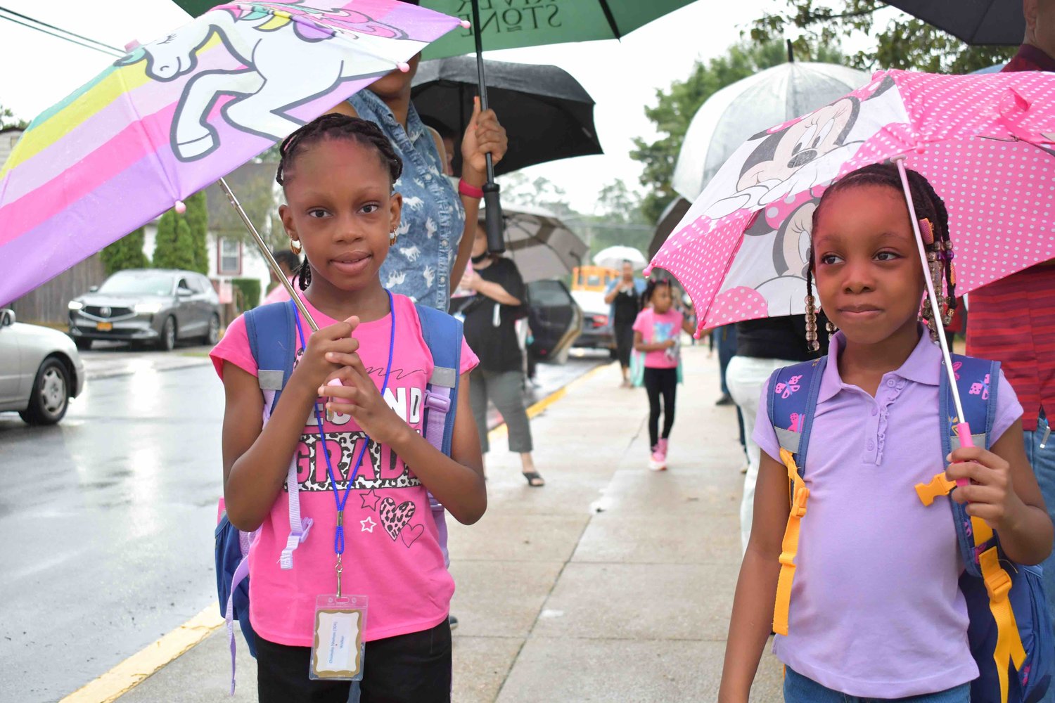 Chiamaka, age seven, and her sister Ijeoma, age five prepared for their first day of second grade and kindergarten, respectively, outside of Maurice W. Downing School.