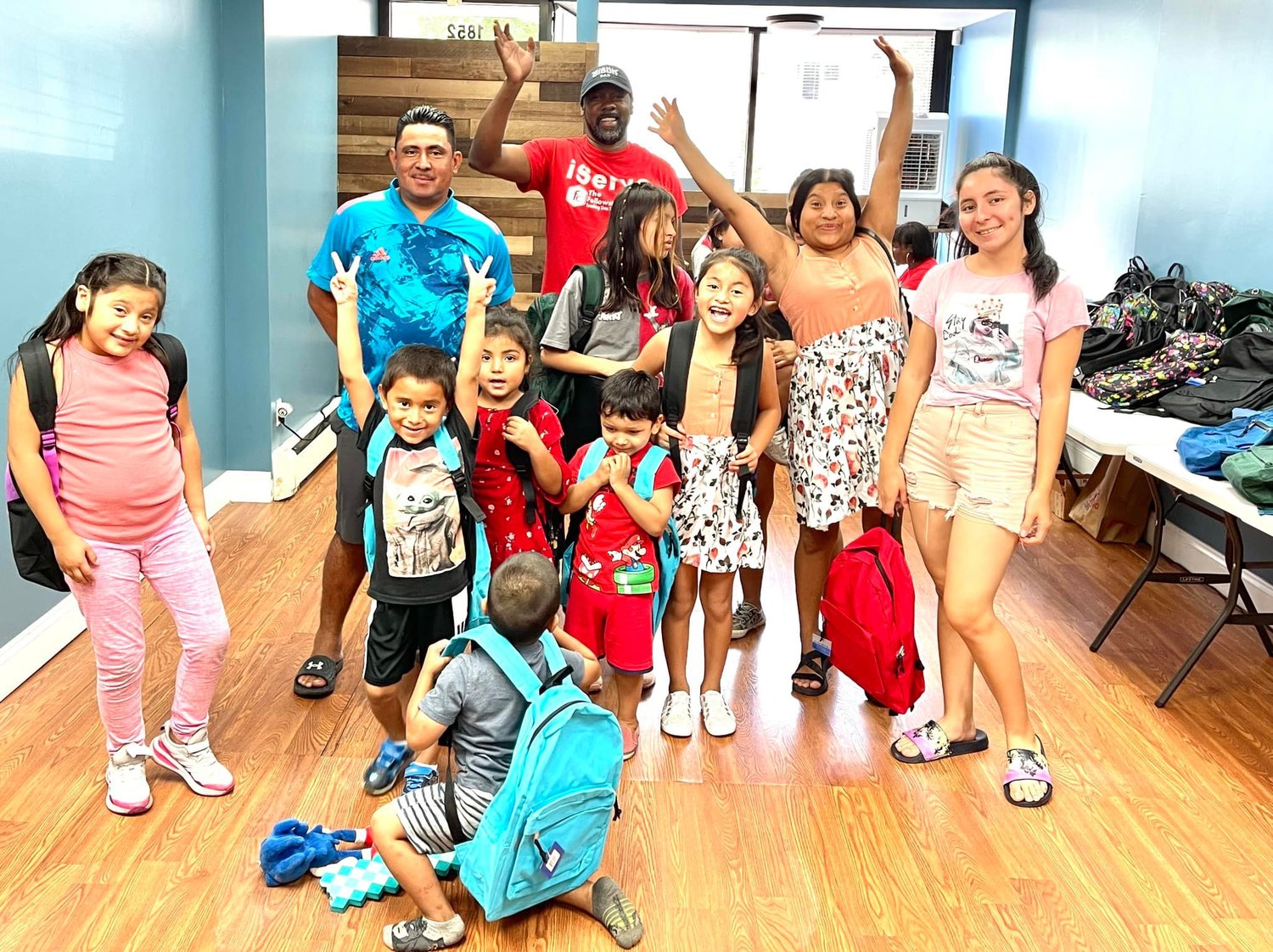 The Rev. Tobias Hall, waving at back right, founder and senior pastor of the Fellowship Center, gave away more than 100 donated backpacks to Baldwin schoolchildren last Saturday.