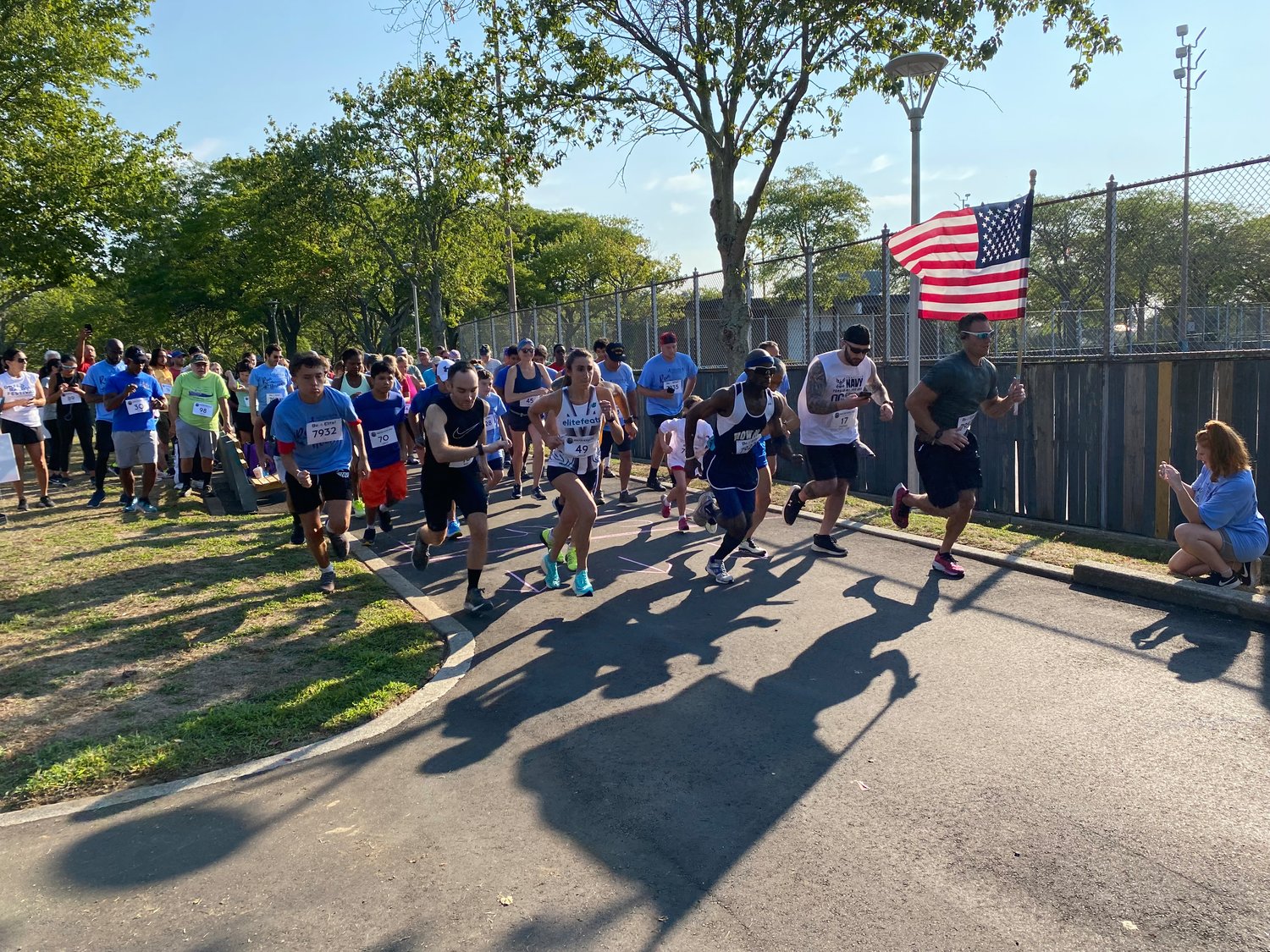 Greg Waxman, holding a flag on the right, Jonathan Davis, to his left, and other participants started the 5K race.