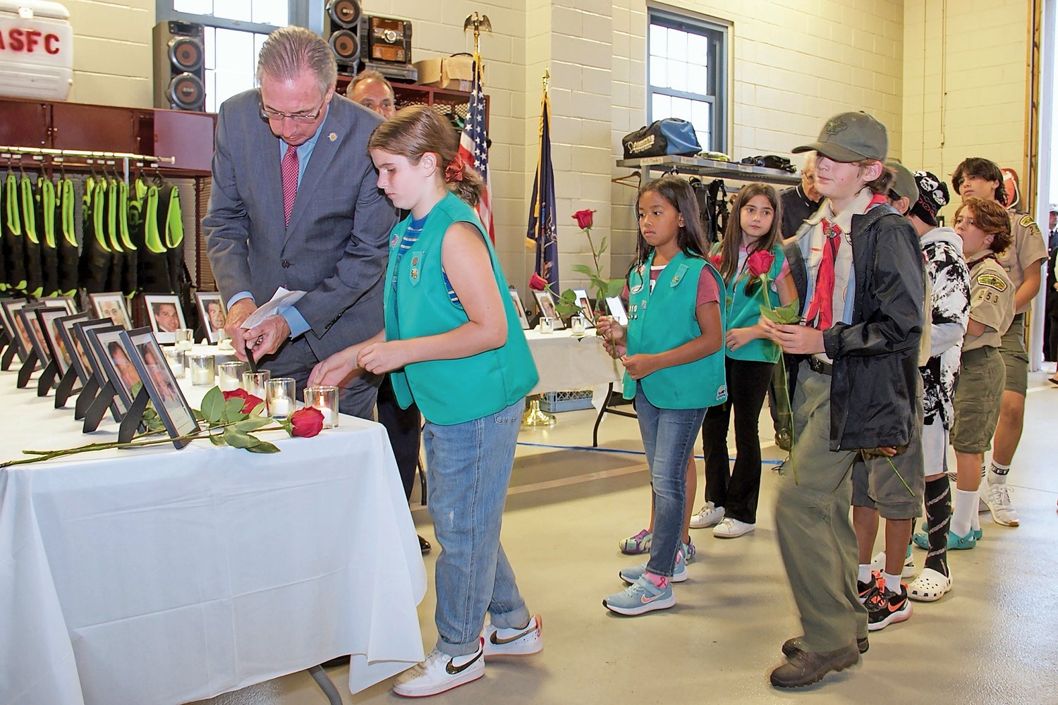 Boy Scouts participated in the 21st anniversary Sept. 11 ceremony in Oyster Bay by laying a rose next to the photographs of the victims, as State Sen. James Gaughran lit a candle.
