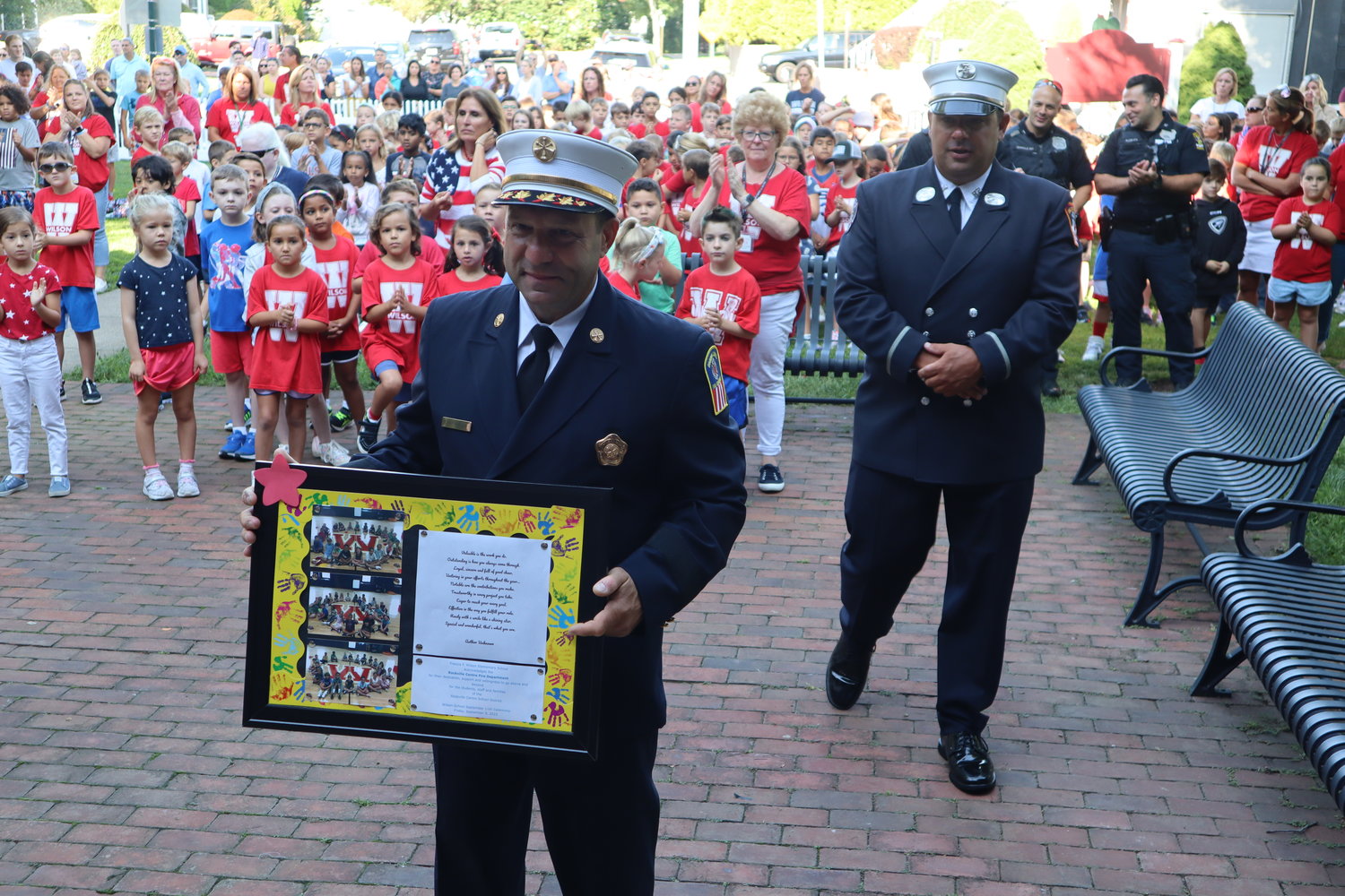 Members of the Rockville Centre Fire Department receive a plaque, provided by Wilson Elementary students, honoring them for their service.
