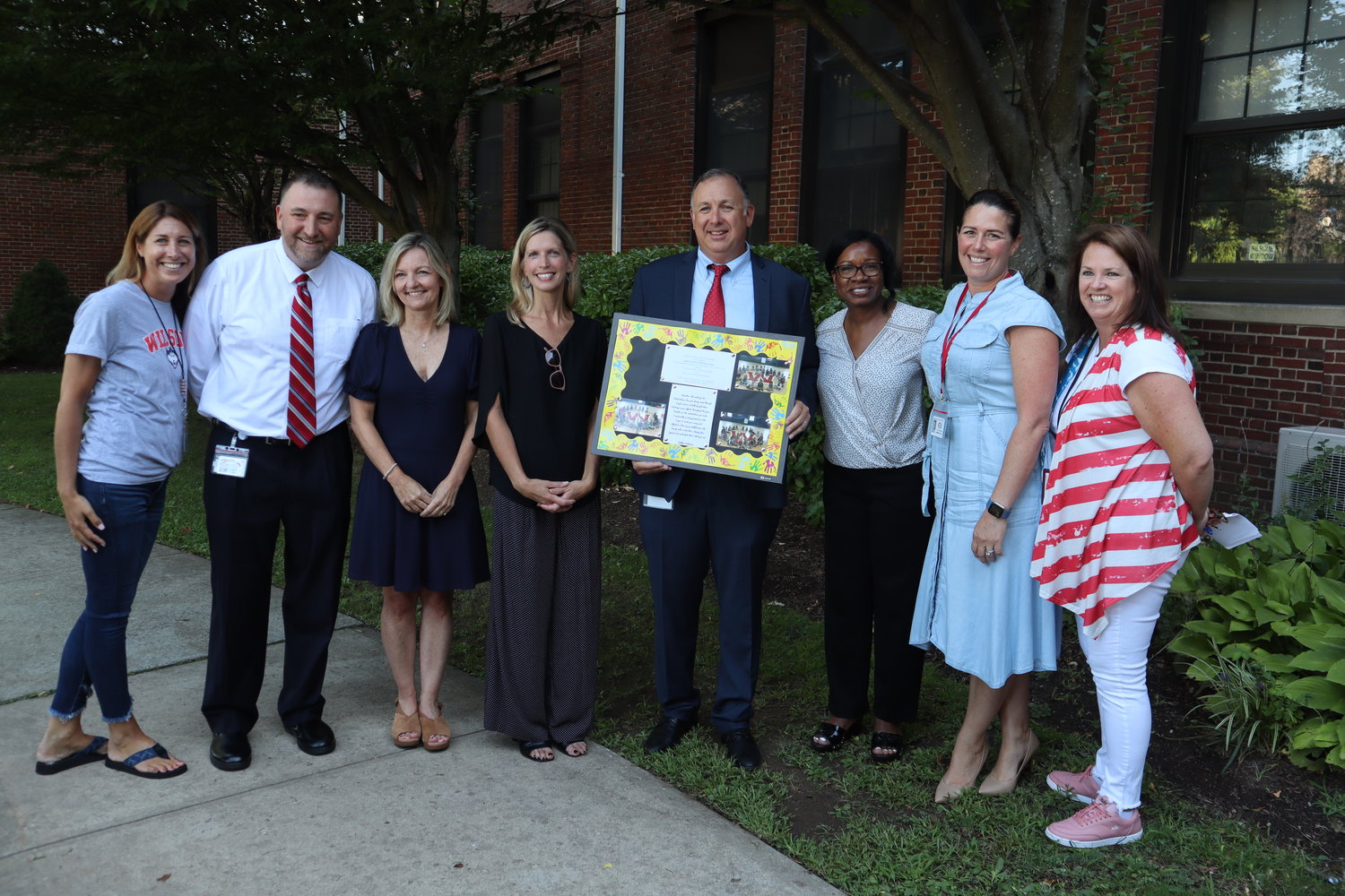 Wilson Elementary School teachers, faculty, administrators, and members of the Board of Education join Superintendent Matthew Gaven, at center with plaque, during Spirit Day.