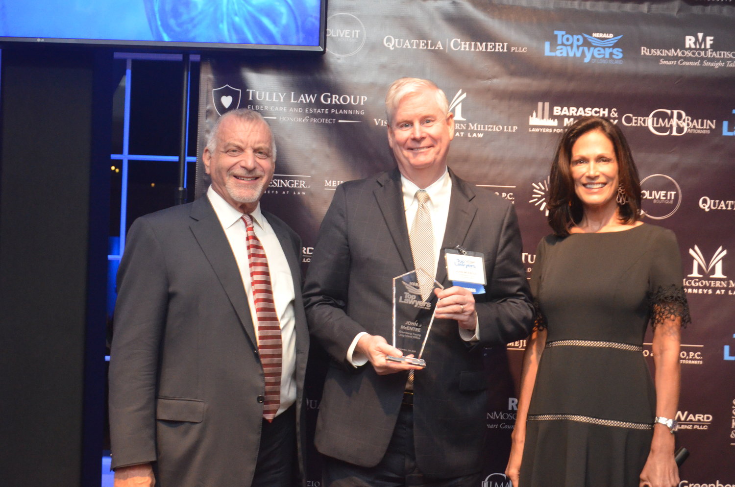 John McEntee from Greenberg and Traurig LLP poses with his crystal award in between Cliff Richner and host Judy Goss. McEntee has been selected to head up the Greenberg and Traurig LLP Long Island office.