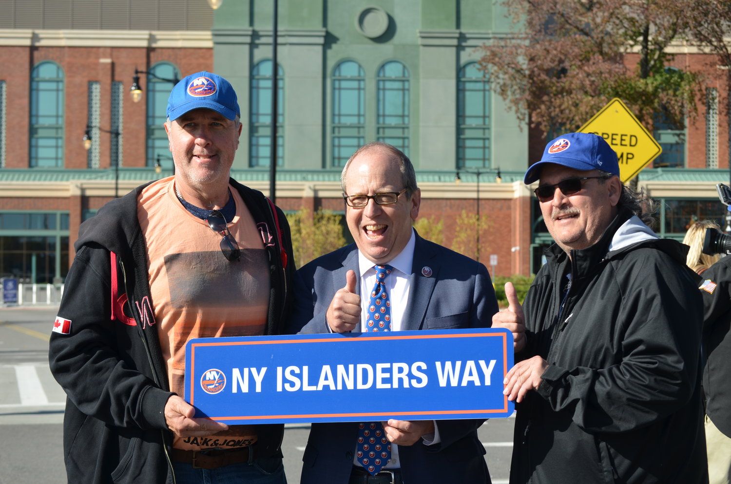 Holding the new NY Islanders Way sign outside Elmont’s UBS Arena were, from left, Dale Hayes, an Islanders fan who lives in Canada, team co-owner Jon Ledecky and Hayes’s friend Joe Mesa.
