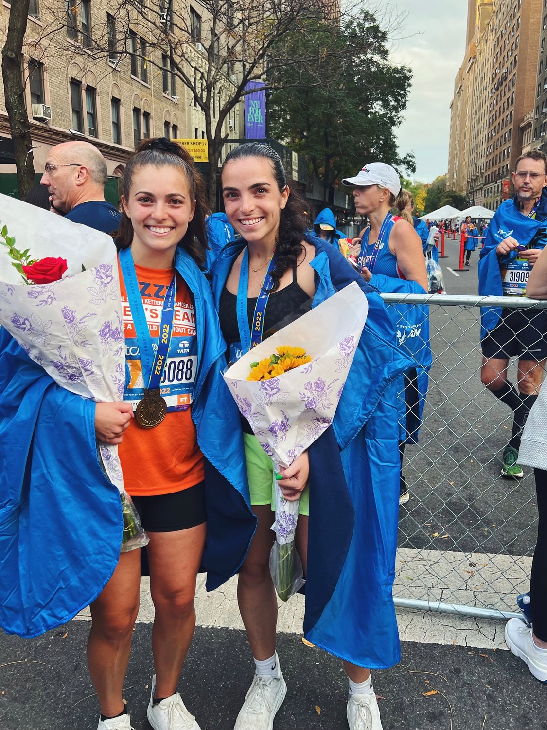 Isabelle Grillo, left, and her sister Sophia Grillo receive a warm welcome from friends and family members at the finish line.