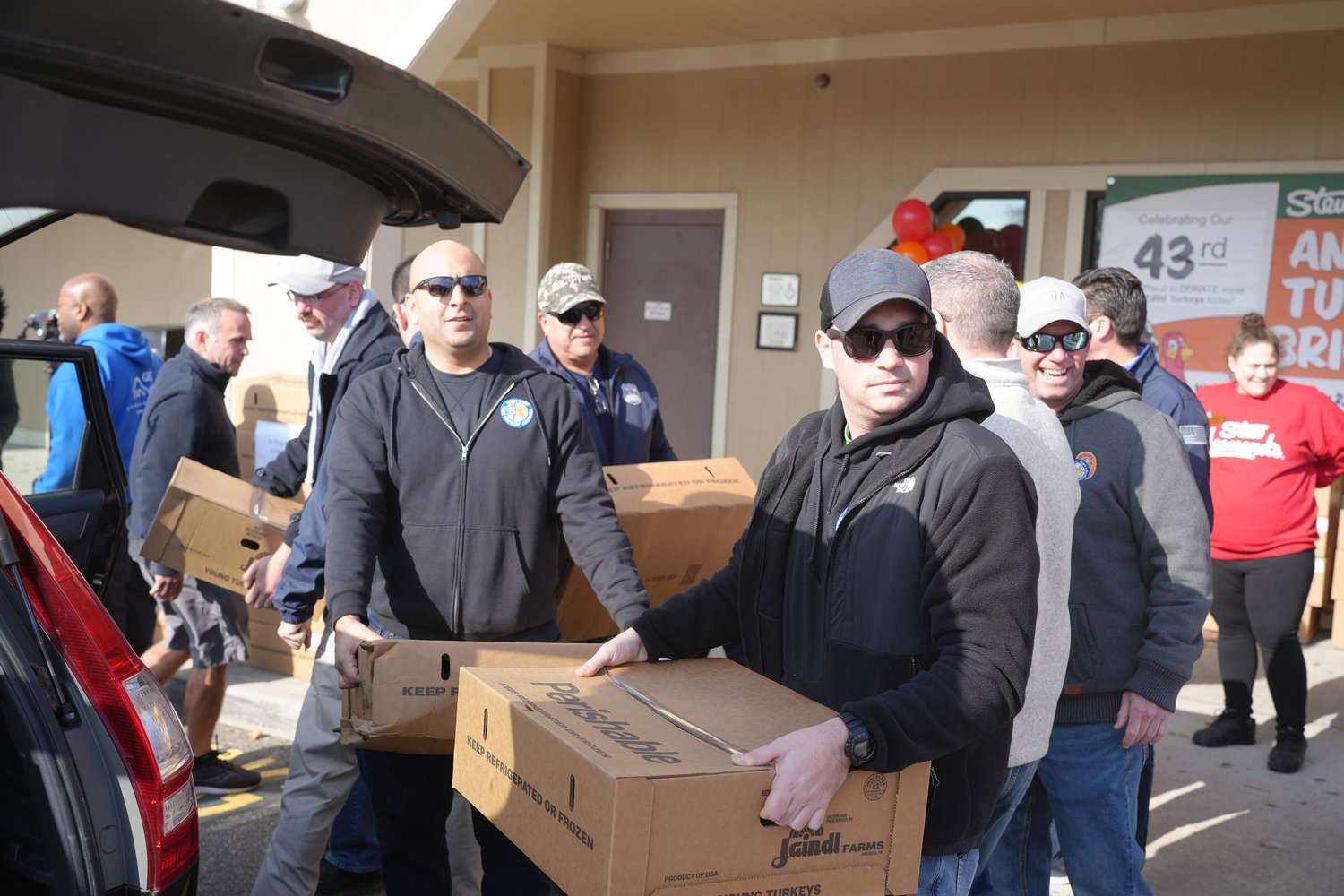 Lou Dileonardo, near right, and Michael Diclemente, far right, of the Nassau County PBA, helped pack boxes of turkeys into the vehicles of the beneficiaries.