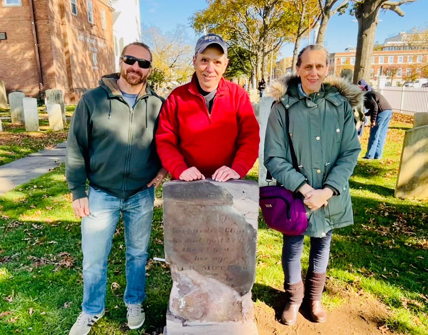 Daniel Baxt, Clowes descendant Bruce Williams, and St. George’s warden Reine Bethany discussed an 1833 Clowes gravestone that Williams is restoring in St. George’s churchyard.