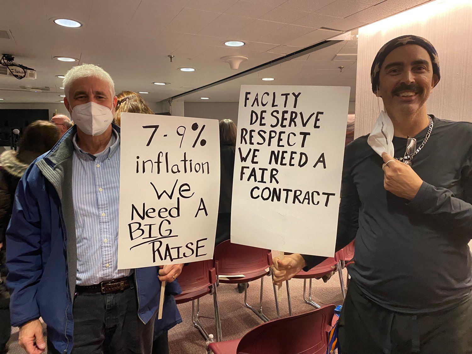 Professor Ricardo Santos and Nassau Community College Federation of Teachers union vice president David Stern hold signs calling for the school’s board of trustees to offer full-time faculty members what they consider to be fair contracts.