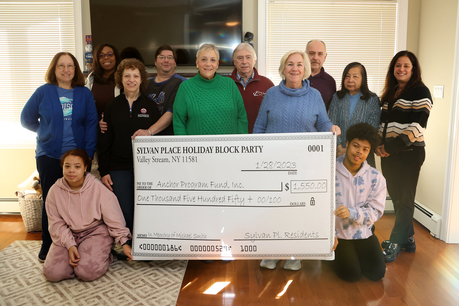 Despite not having a normal block party this past holiday season, neighbors on Sylvan Place raised money and donated $3,100 to two organizations, including $1,550 to the Anchor Program Fund. Above, Rosalie Machalow, Sherise Dowling and her children Candice and Marcus, Sheryl and Alex Carr, John McGovern, and Wally and Carole Schroeder present checks to Susan Cuoccio and Mary Ann Hanson, of Camp Anchor, and Ronni Gould, of the Sunrise Association.