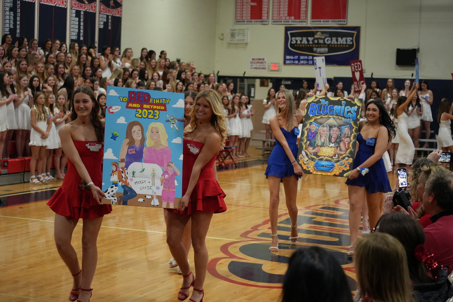 Red team captains Catie Morgan and Molly Munro and Blue team captains Maggie Chifriller and Alayna Marzolini present their themes during the poster and revue night event on Thursday.