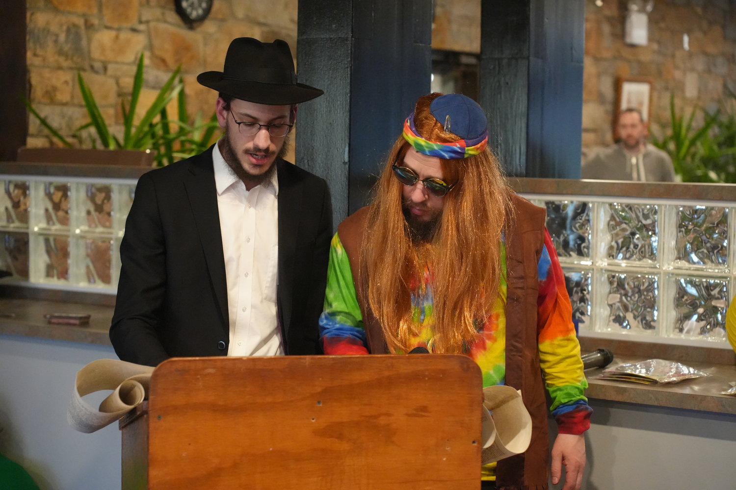 Rabbi Kramer, dressed in tie-dye, read the Megillah with a Yeshiva student at the Chabad of Merrick-Bellmore-Wantagh’s Purim celebration.