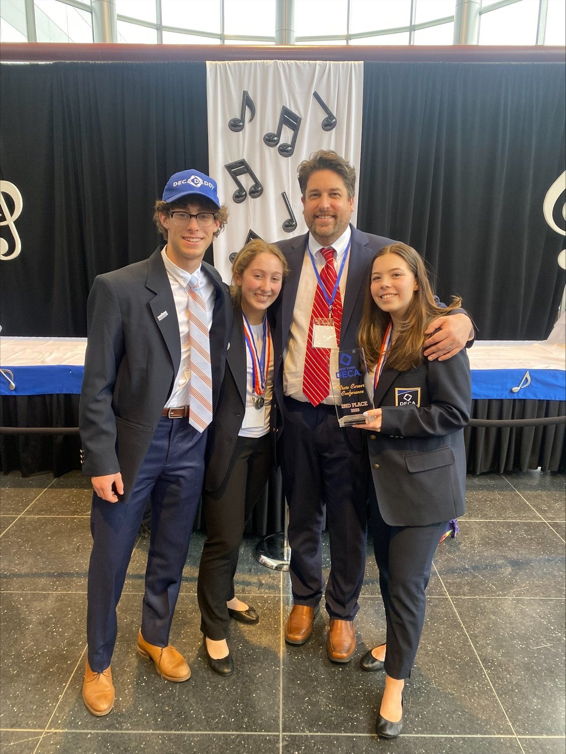 Gavin Goodlad, far left, Hailey Ferraro-Reich, business teacher Peter English and Catherine Medeiros celebrate taking second place overall for their sales project.