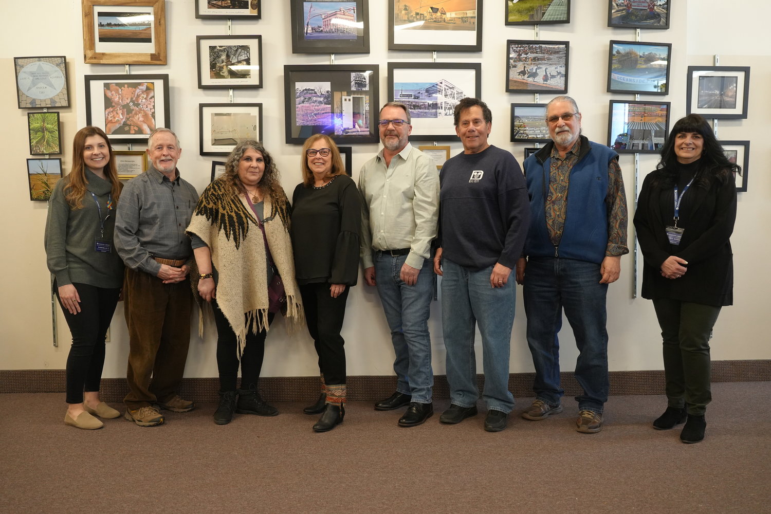 Librarian Gabriella Trinchetta, on left, next to six local artists displaying their work at the Photography Club art reception at the Oceanside Library, with library director Chris Marra, far right.