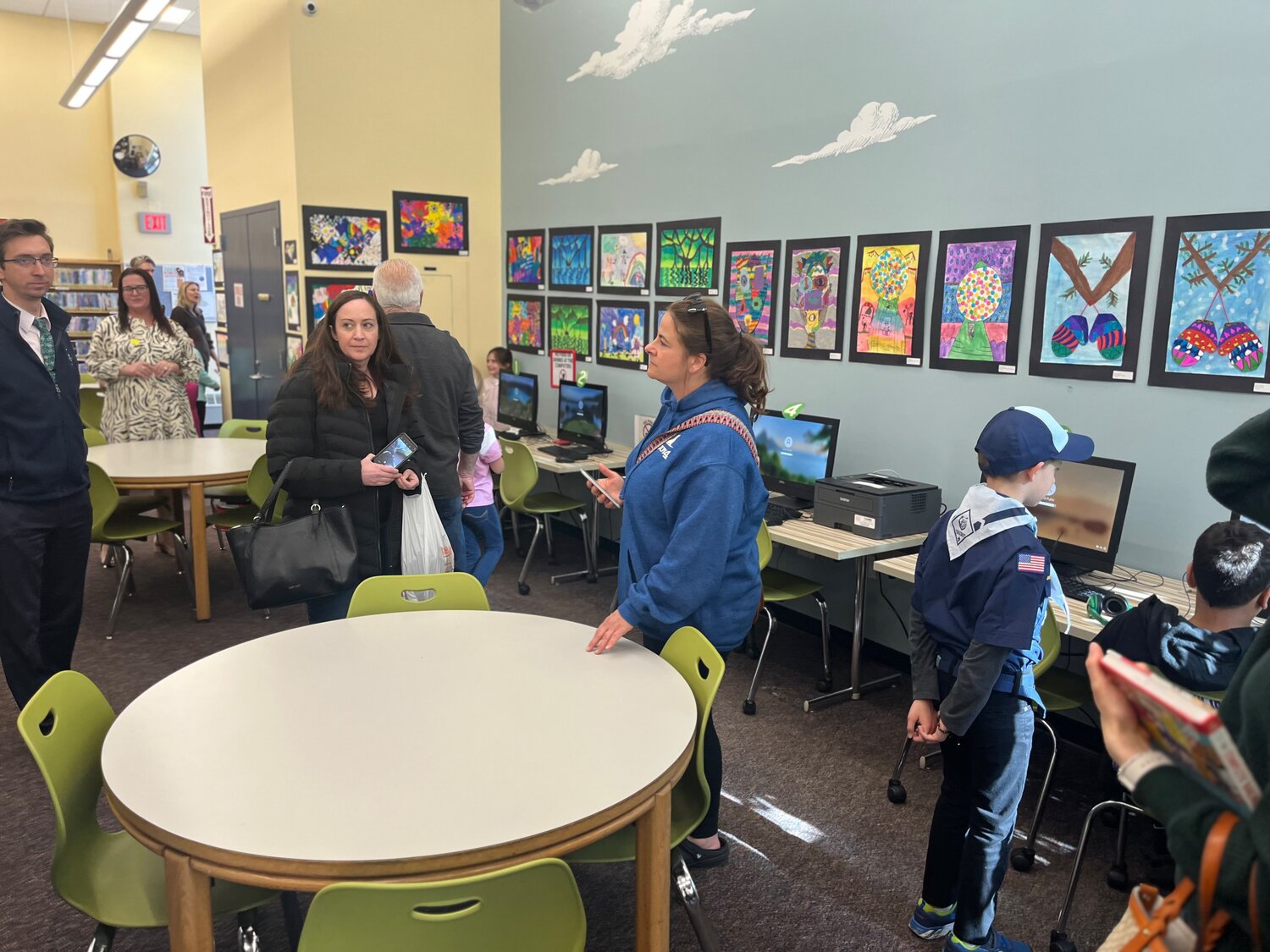 Students and parents explore the different exhibits hanging throughout the library.