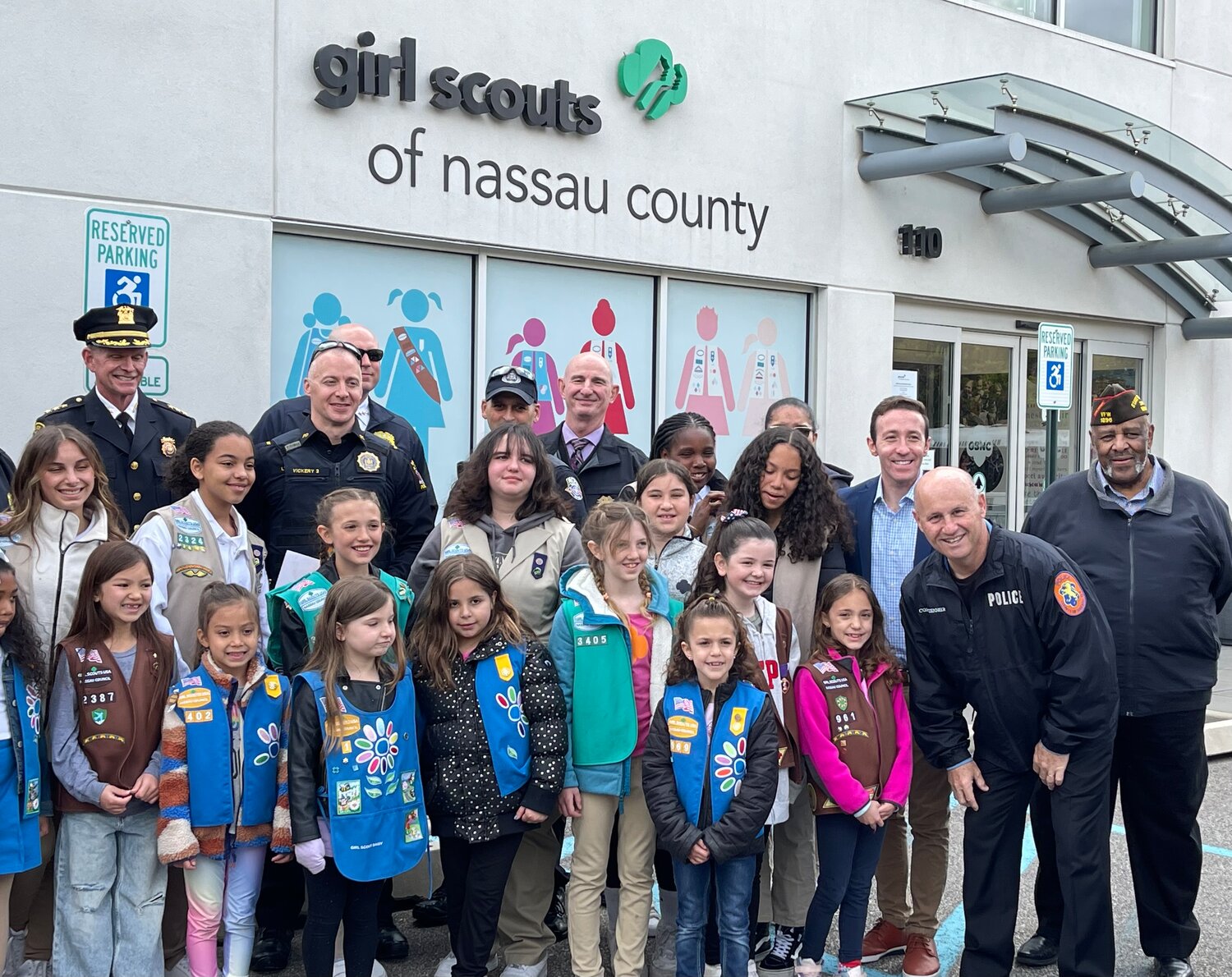 three Girl Scouts from North Bellmore, Aria Williams, Arianna Coutu and her sister, Gemma Coutu, bottom right, participated in a cookie collection for Operation Hometown Hero. They got to meet members of the military, elected officials and dozens of police officers at the Girl Scouts of Nassau County headquarters in Garden City on May 3.