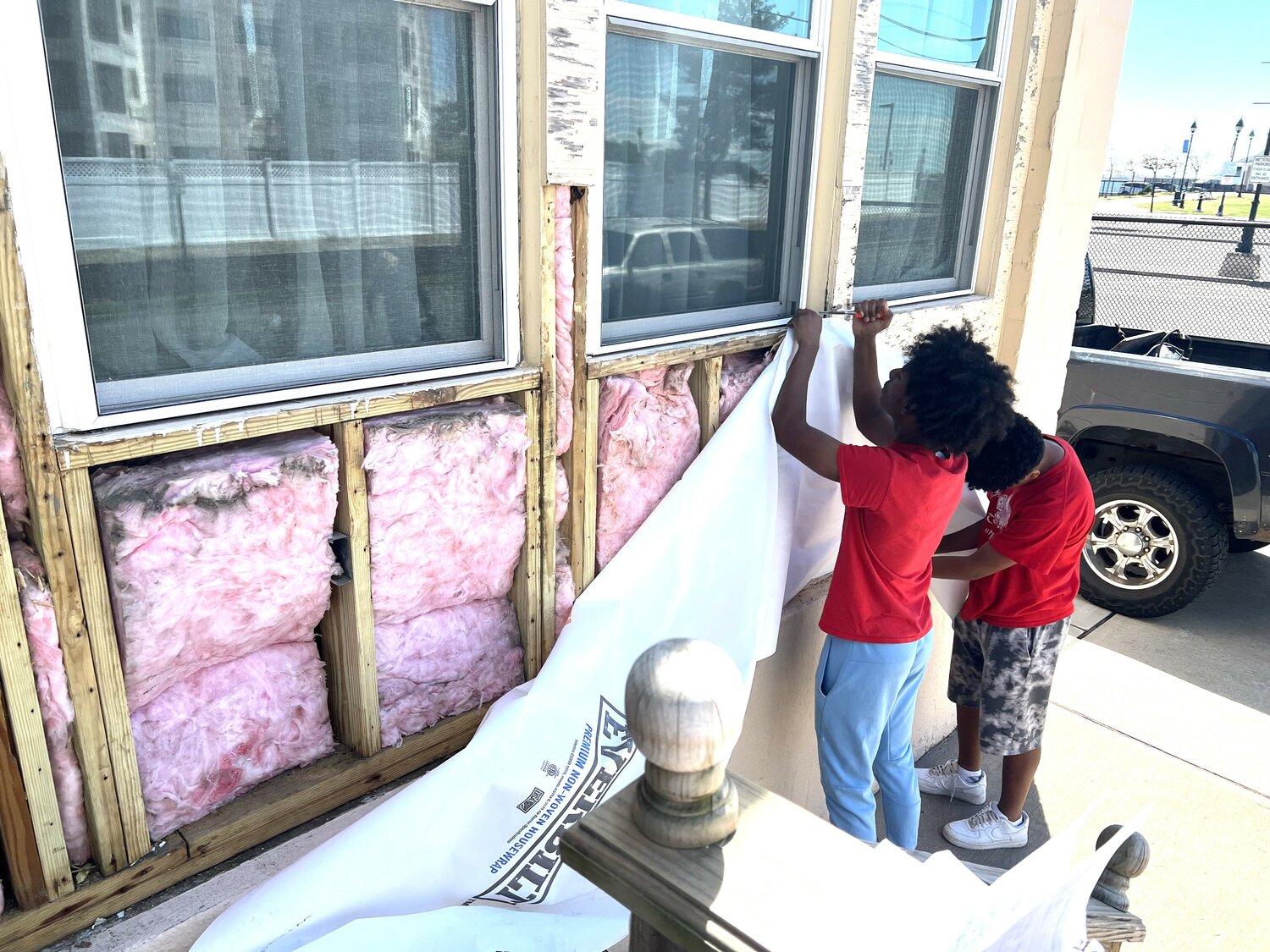 The brothers removed a special plastic covering from the fascia of the Post 342 building, exposing the still-useful fiberglass insulation, which Jeremiah will augment during the renovation of the wall.