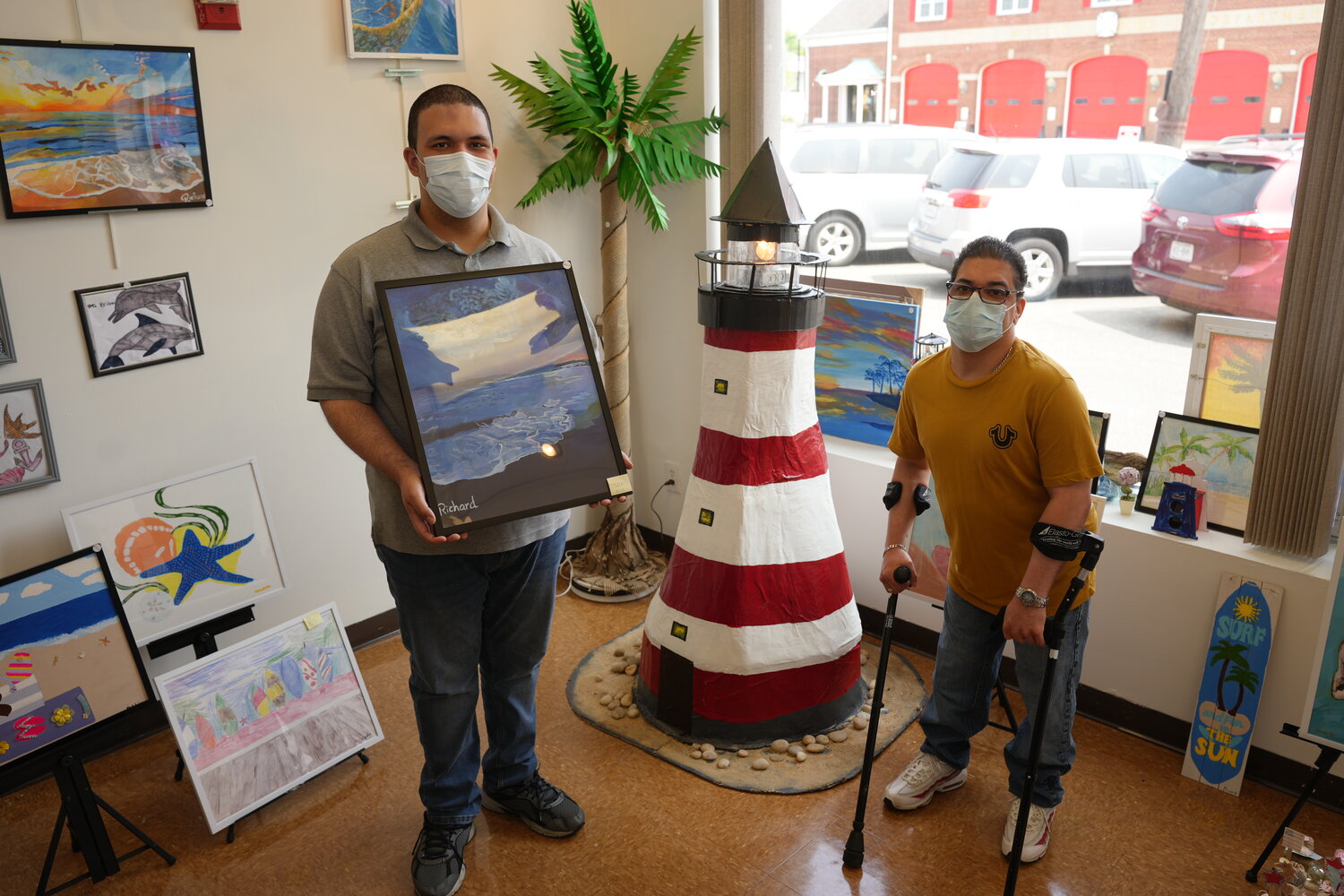 The AHRC Nassau East Meadow Art Gallery’s newest exhibit is titled ‘A Day at the Beach.’ Davis Hernandez, right, helped make the 5-foot-tall papier-maché work of art, and Richard Infante painted beach scenes.