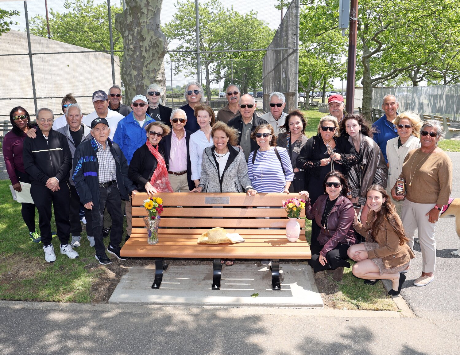 Friends of Jay Fagin, including Hempstead Town Councilwoman Laura Ryder, middle in white, gather at a bench dedicated to Fagin in Oceanside Park. The cowboy hat he wore everywhere was its first occupant.