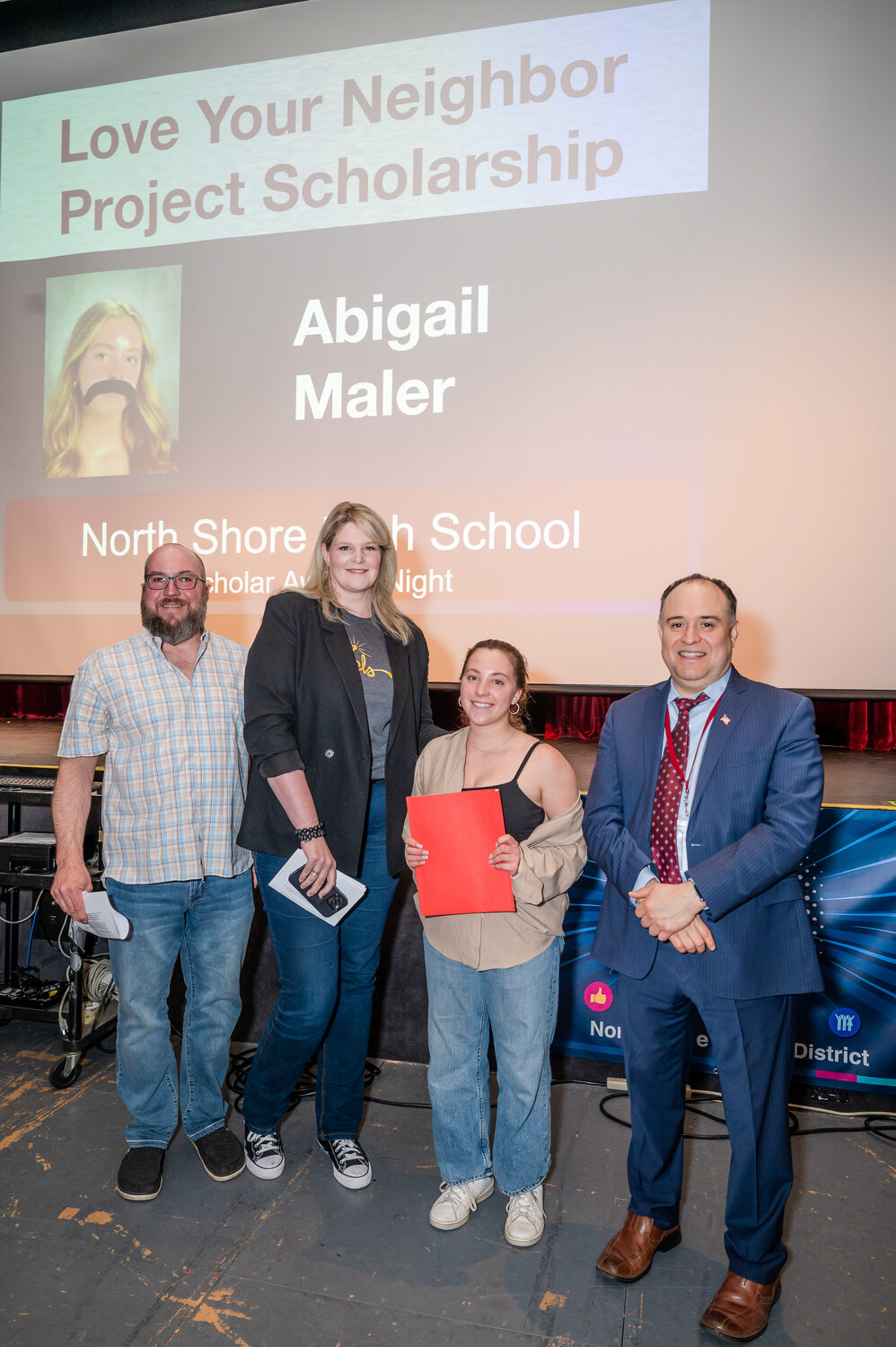 Abigail Maler, second from right, of North Shore High School, was given a Love Your Neighbor Project Scholarship by Sean Llewellyn, left, the project’s logistics neighbor, Jennifer DeSane, their strategic neighbor, and Eric Contreras, the high school principal.
