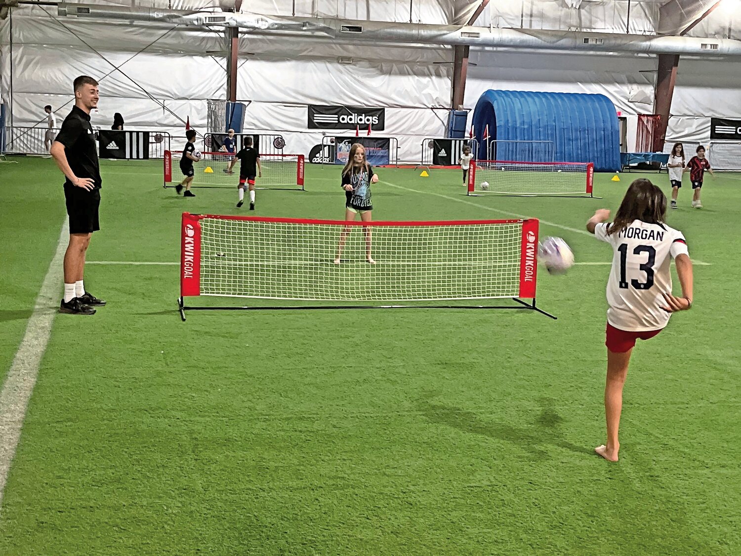 The World Cup game might be on television, but that didn’t stop children from playing soccer-tennis on one half of the field at the Globall Sports Center.