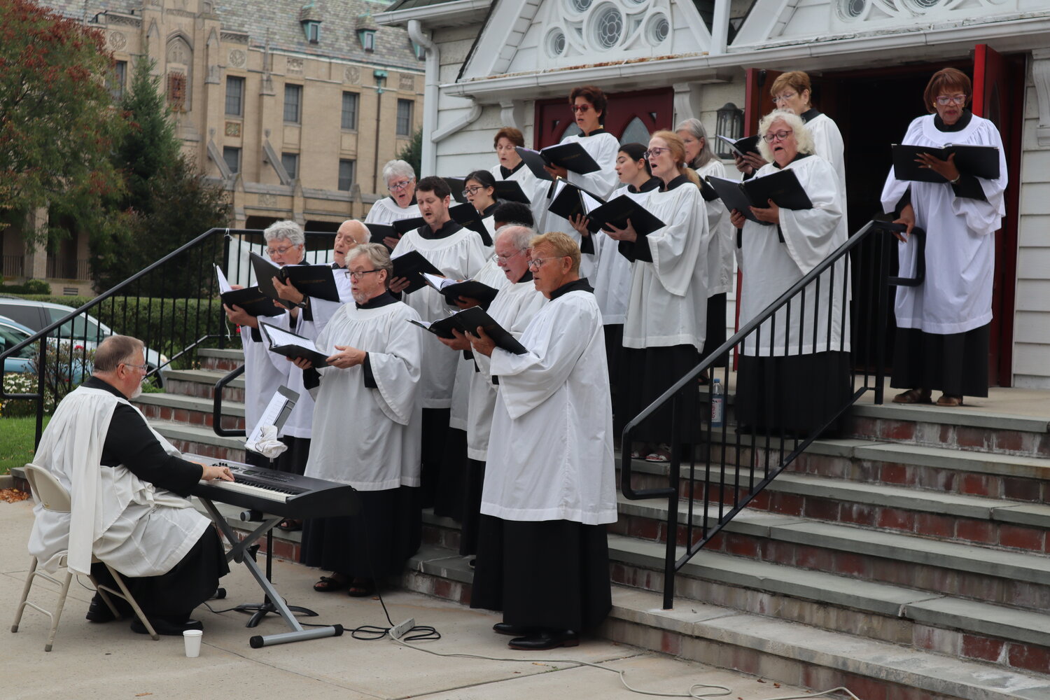 Choirmaster Ken Dyer and the Ascension Church Choir perform on the church steps along N. Village Avenue.