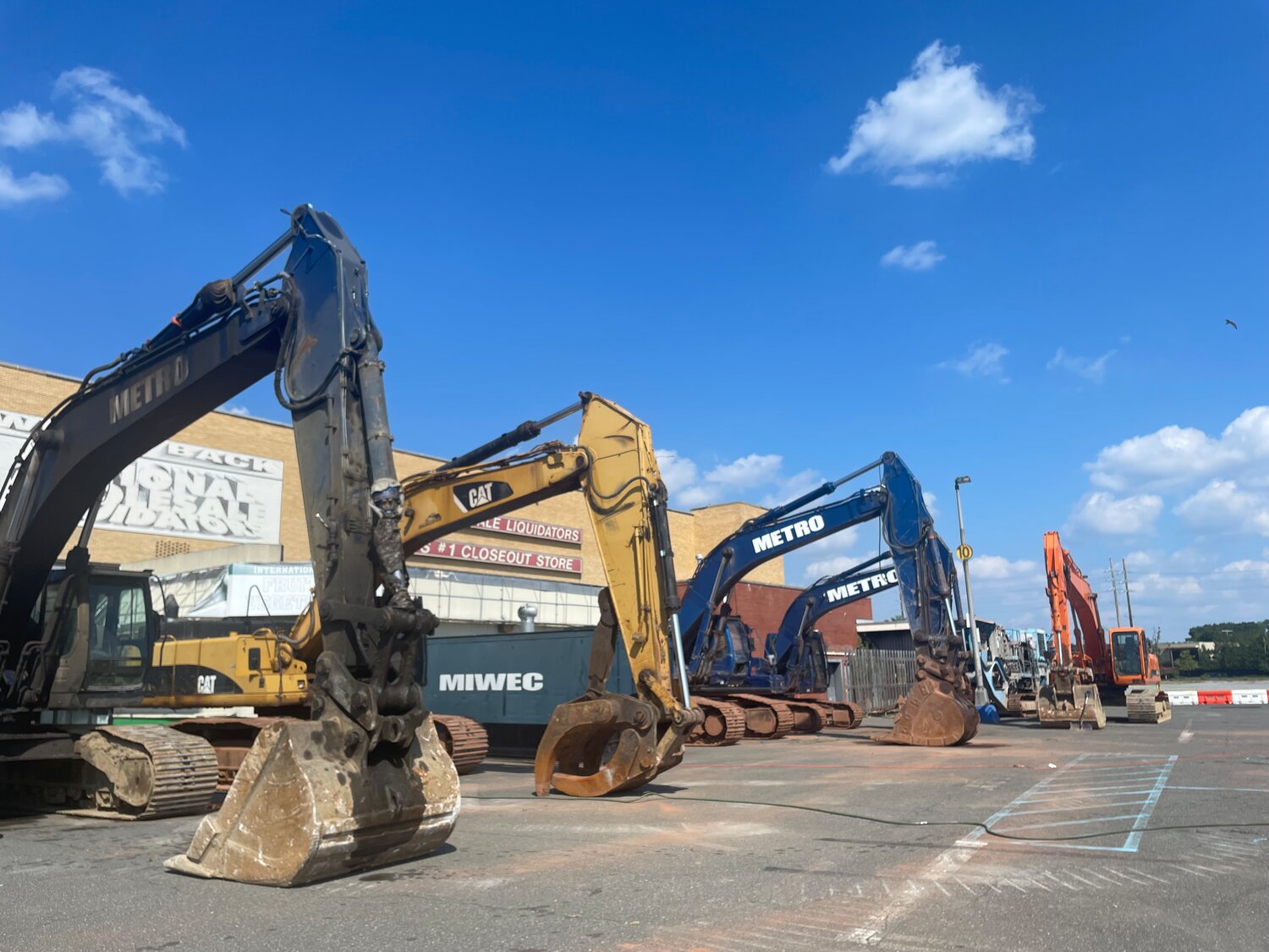 Excavators lined up in front of National Wholesale Liquidators, which has been abandoned for years.