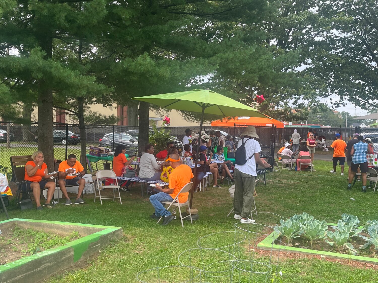 Attendees sitting and enjoying the free food and drinks, music, and getting ready to harvest the fresh fruit and vegetables straight from the earth of the garden to their hands.