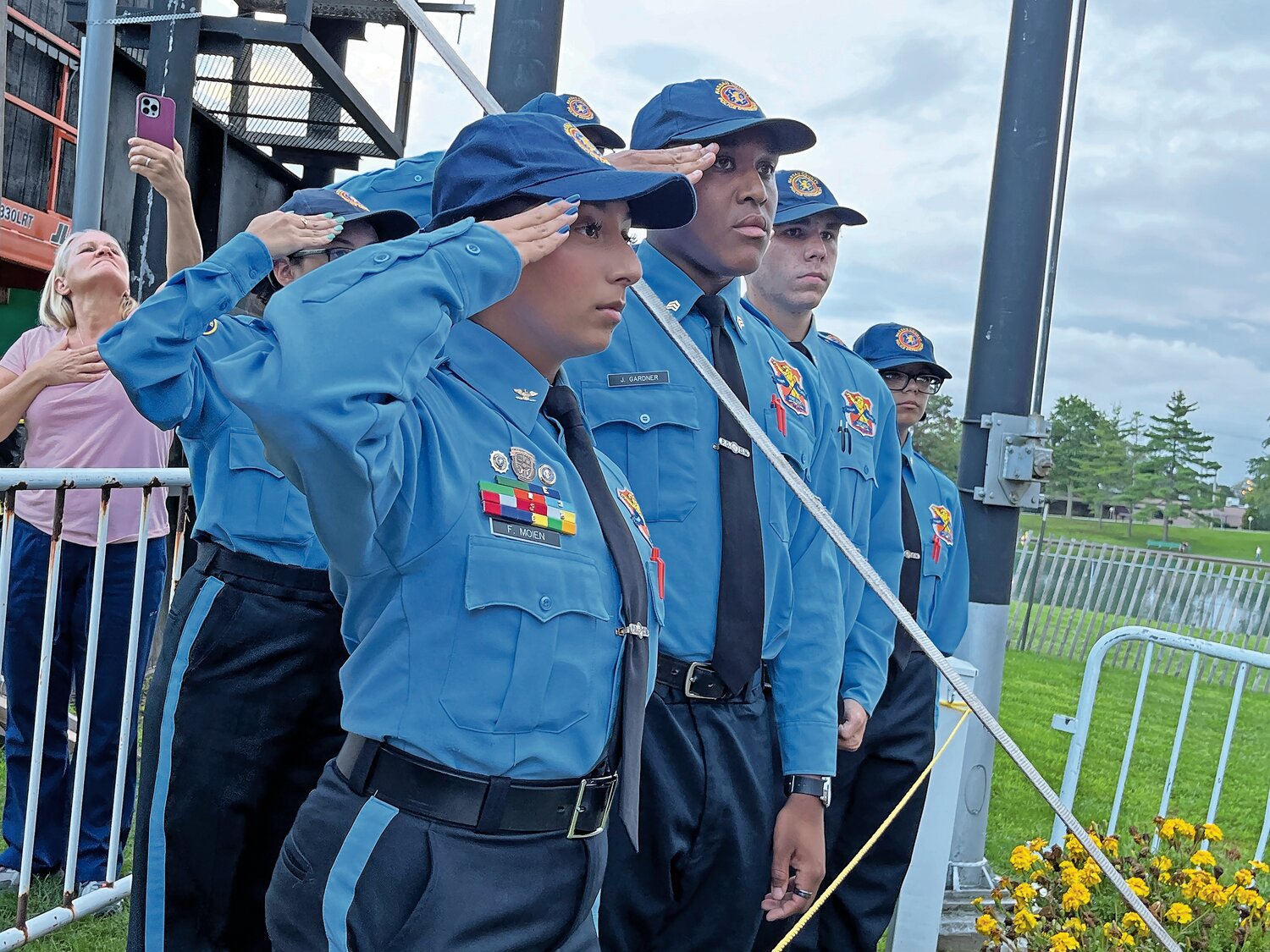 Nassau County law enforcement Explorers salute while Christopher Macchio sings the national anthem during the 9/11 Remembrance Ceremony at Eisenhower Park.  Such ceremonies are important, County Executive Bruce Blakeman said, not just to remember those who we lost, but to ensure younger generations like these Explorers never forget.