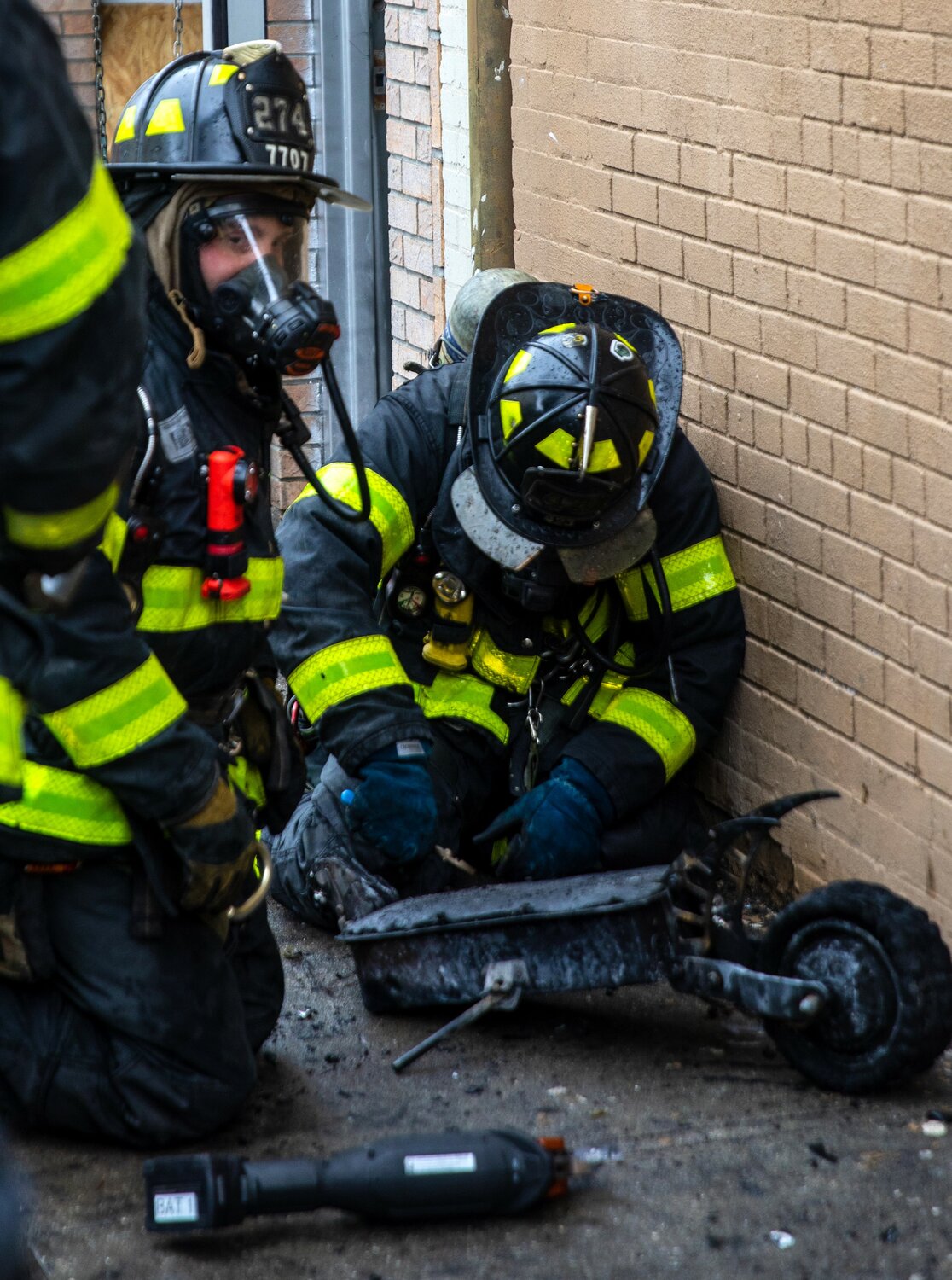 New York City firefighters wearing breathing masks as they extinguish a battery fire on a two-wheeled scooter.