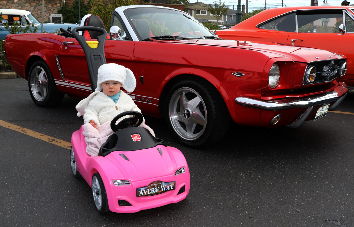 Avery Ludwig (14months) cruising into the Island Park Car Show with  her pink 2023 Avery Way convertible car.  She has her economic and environmental friendly car-non-gas and non-electric.   She was hanging out with other convertibles- 65' Mustang.