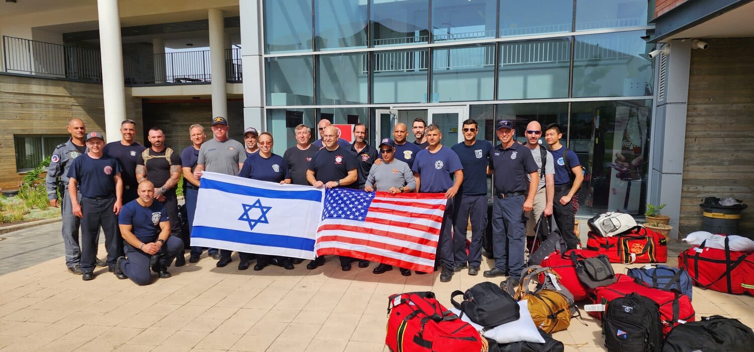 Jason Stukes, seventh from right, and Shoshana Weiner, ninth from left, were among volunteers from across the United States providing aid to Israeli fire departments.